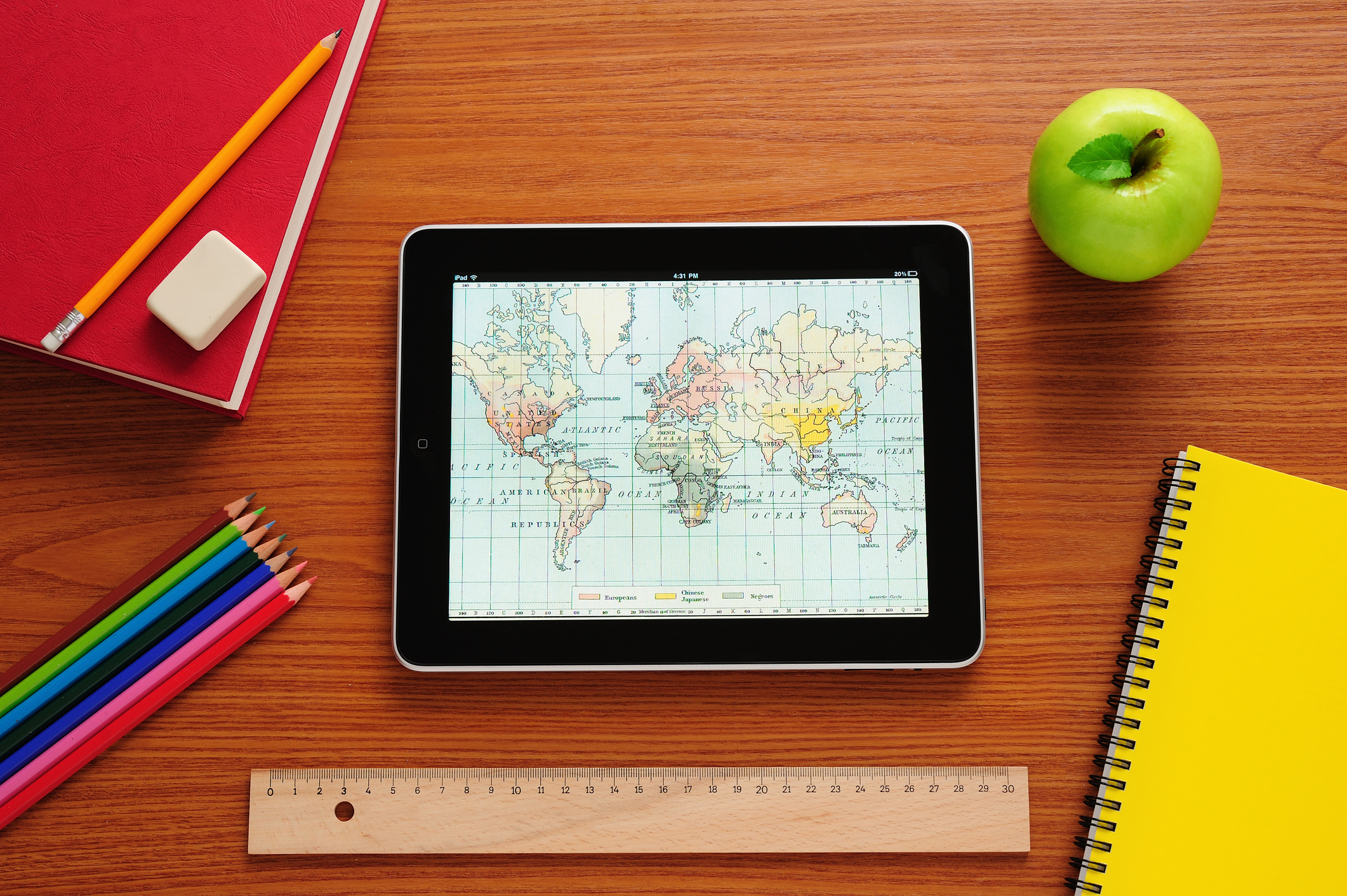 Desk with tablet showing a map, colour pencils, and writing pad Desk with tablet showing a map, colour pencils, and writing pad