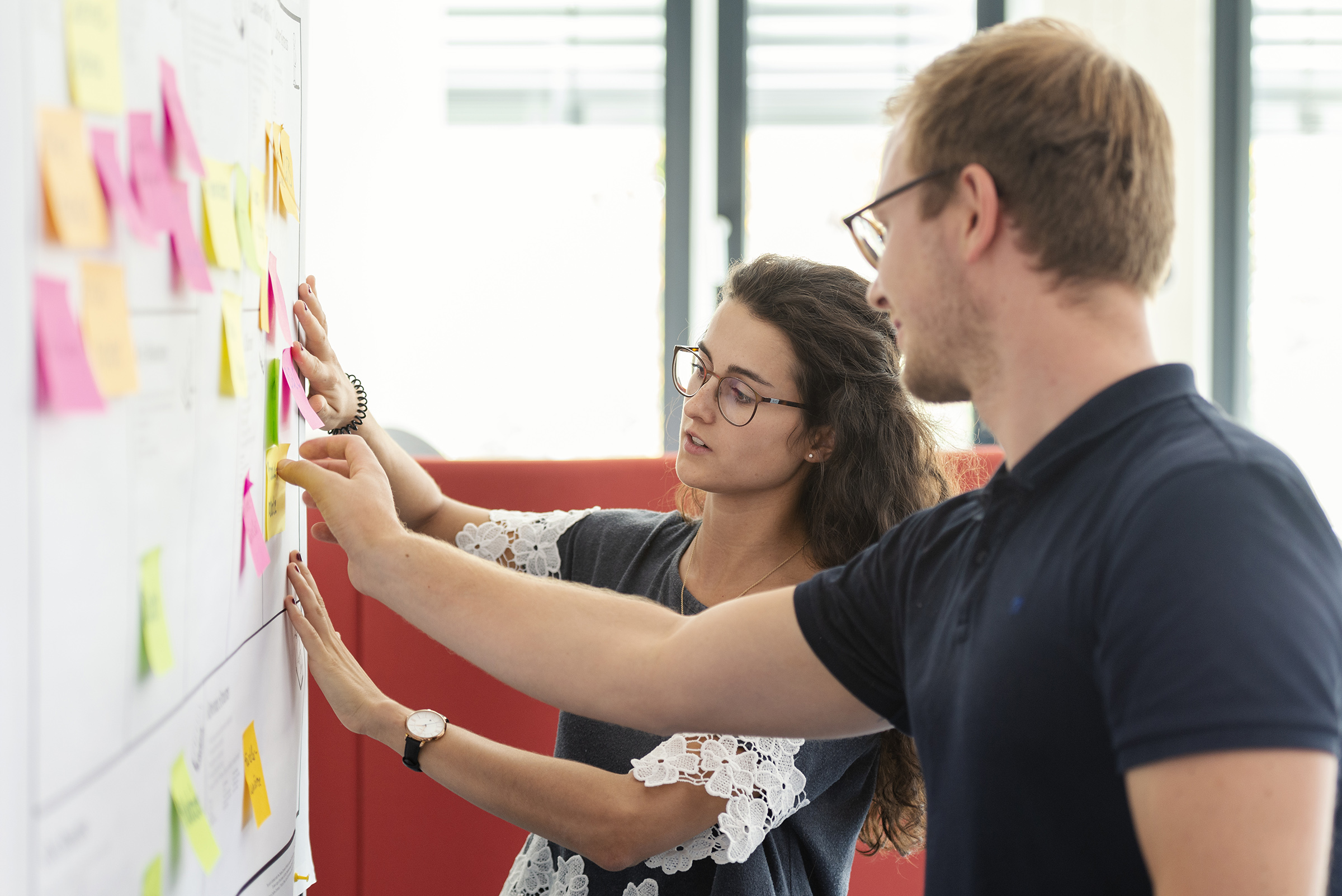 two students putting different coloured notes on whiteboard two students putting different coloured notes on whiteboard