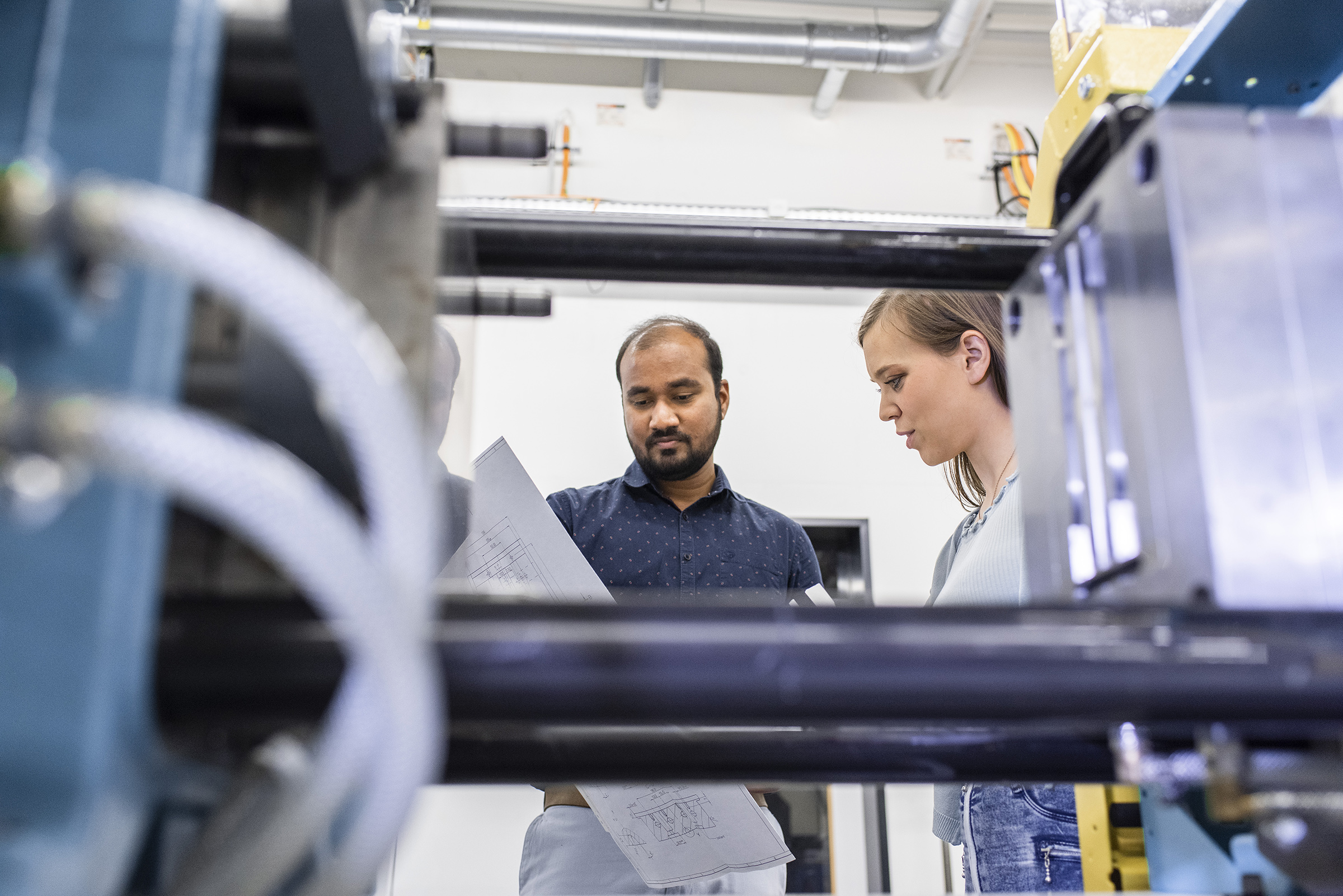 two people looking at a piece of paper, with machine in foreground two people looking at a piece of paper, with machine in foreground