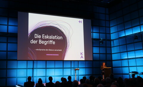 Medientheater des ZKM, Prof. Anja Grunwald auf der Bühne, hinter ihr die Leinwand mit der Titelfolie zu „Eskalation der Begriffe – wie Sprache den Diskurs verschiebt“