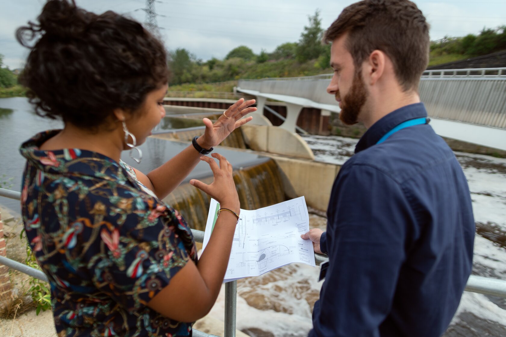 two engineers discussing a project, with a dam in the background two engineers discussing a project, with a dam in the background