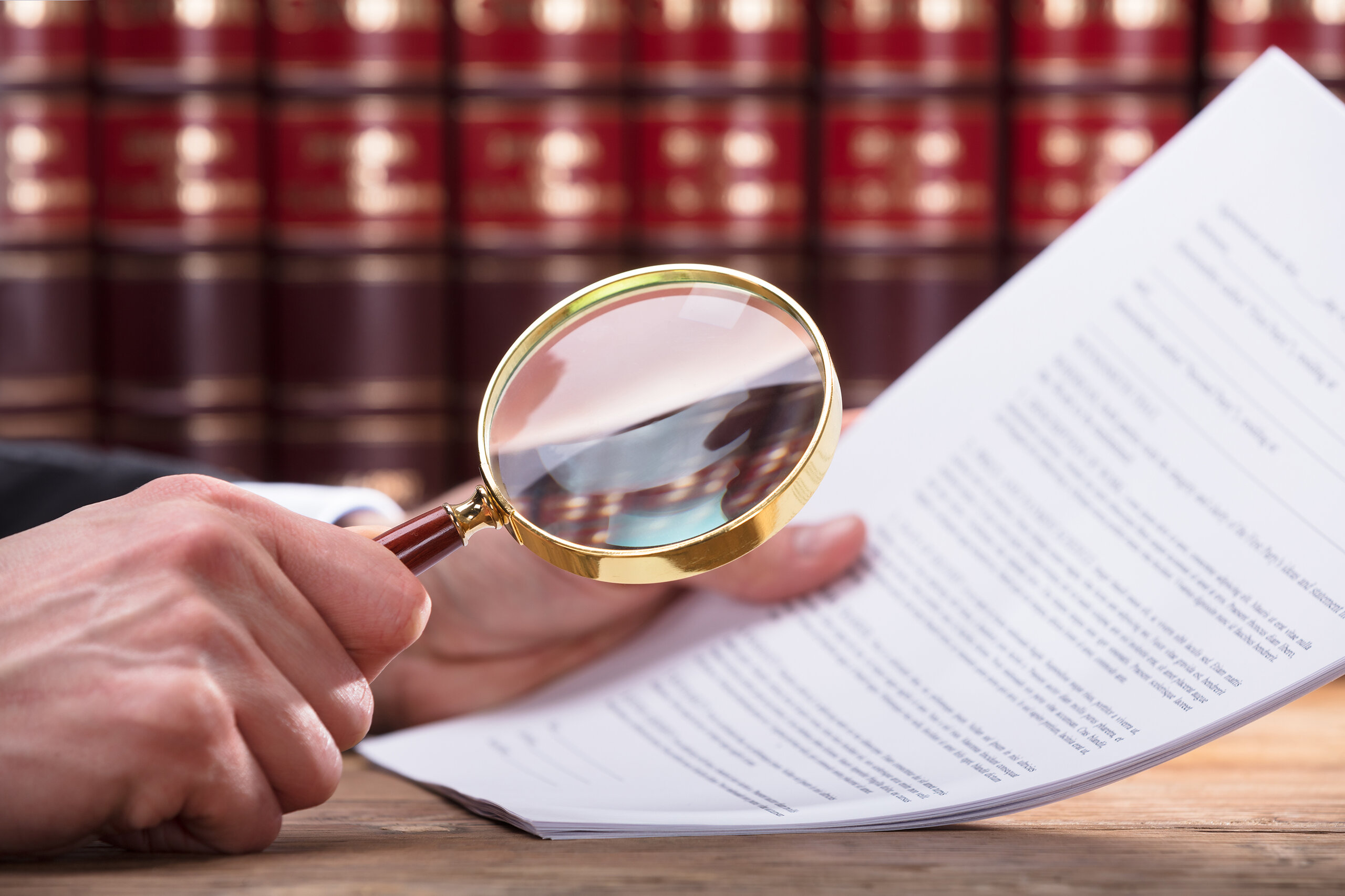 close-up of hand holding magnifying glass to a piece of paper