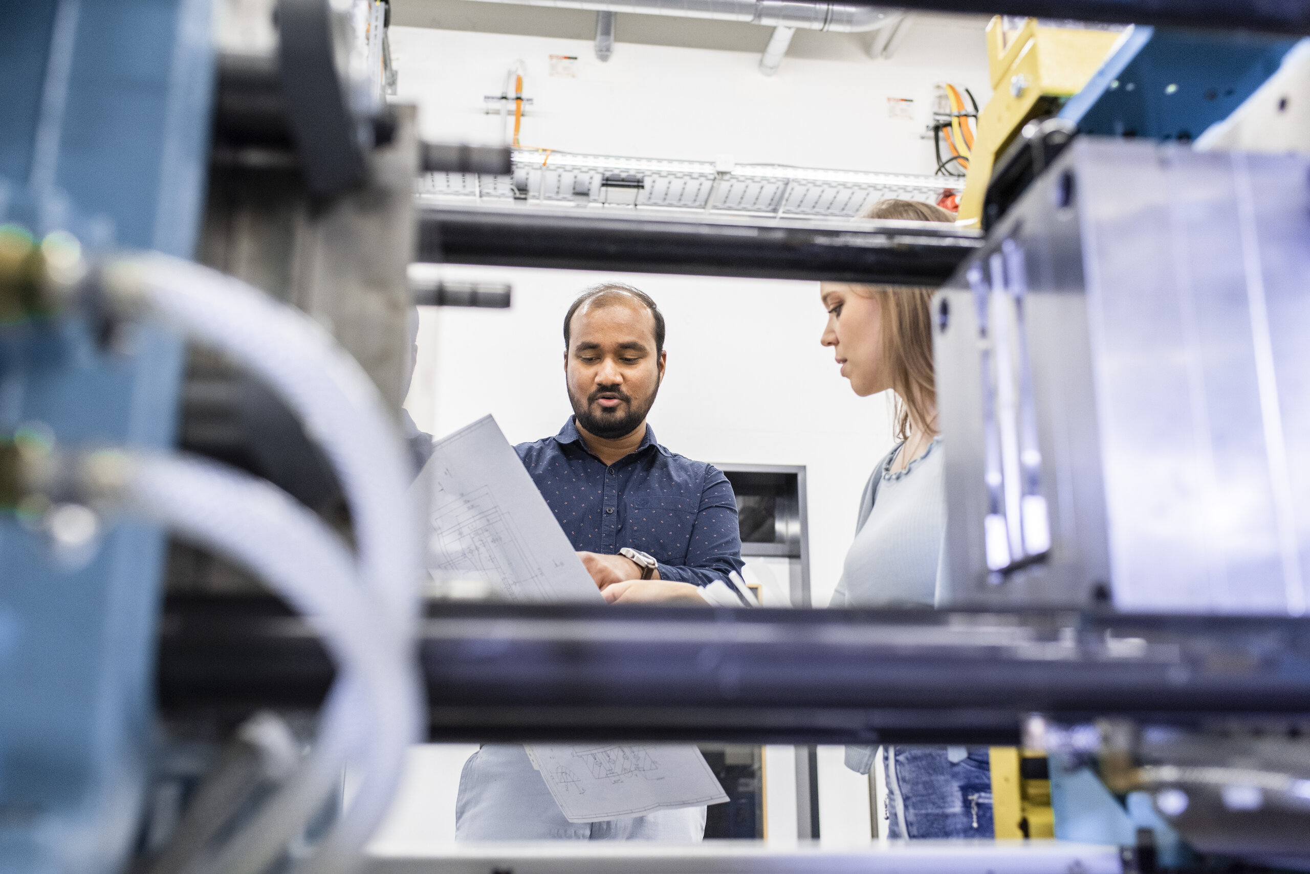 a man showing a woman a piece of paper, with machine in the foreground a man showing a woman a piece of paper, with machine in the foreground