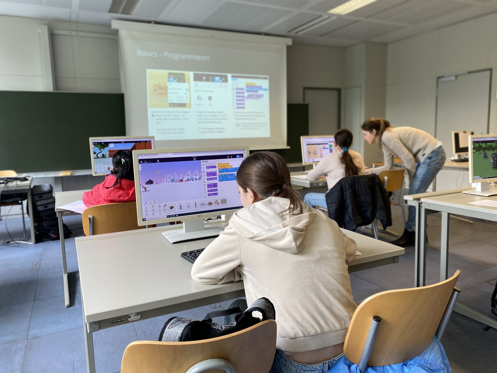 The participants sit at the computer and learn the basics of programming with the CoSpaces app.