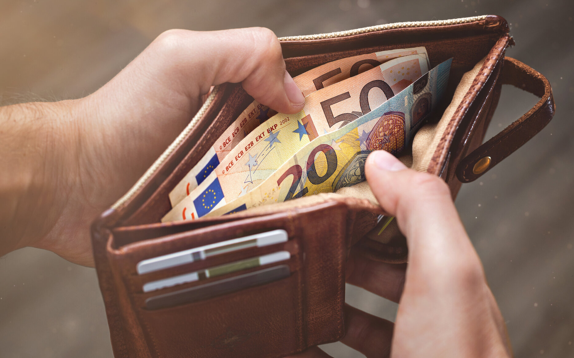 Close-up of hands opening a wallet containing Euro banknotes Close-up of hands opening a wallet containing Euro banknotes