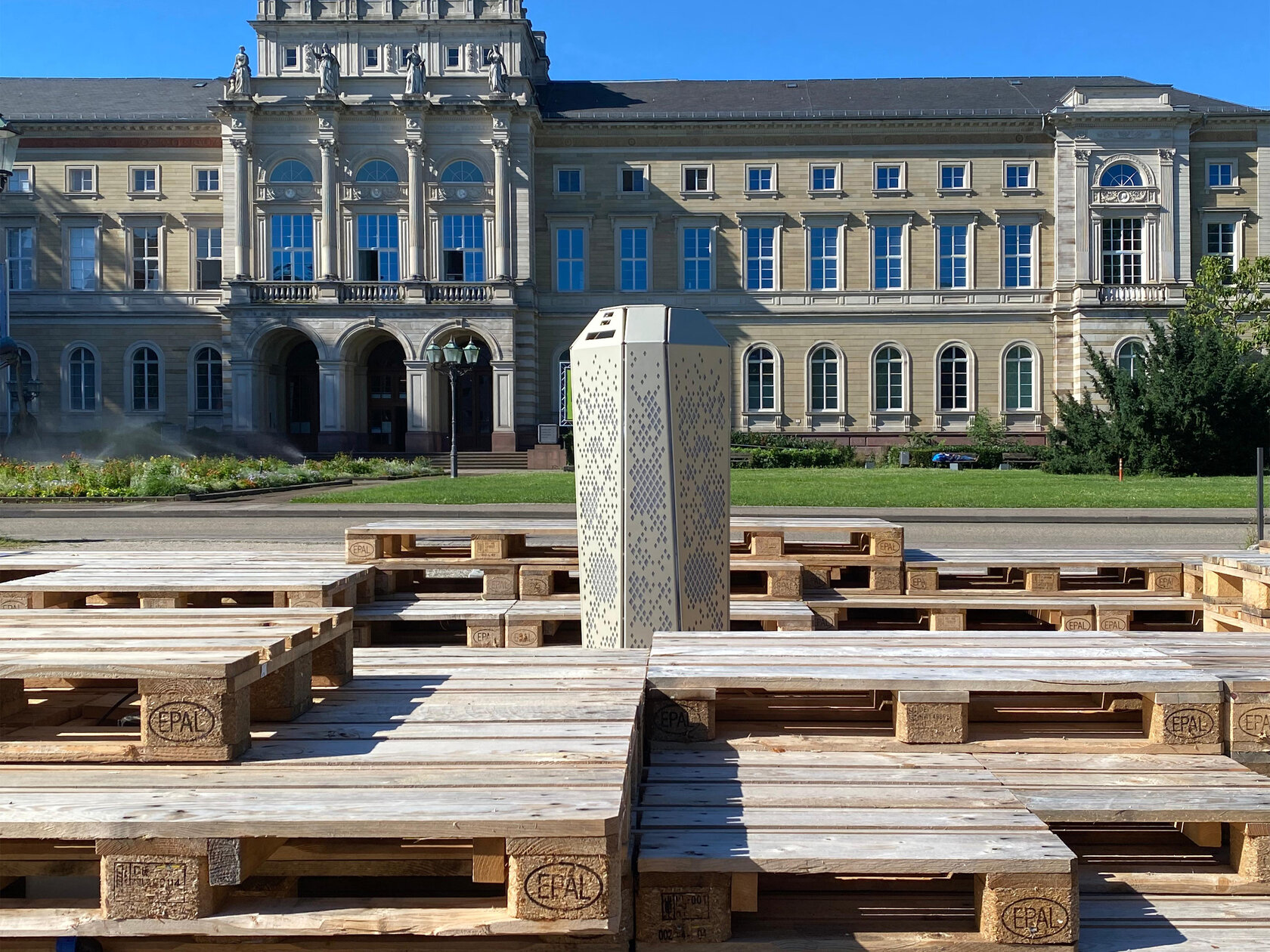 column surrounded by wooden platforms for sitting, in the background is the museum