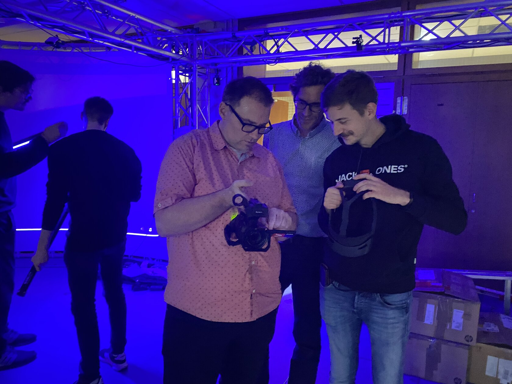 Three men look at a camera display and smile.