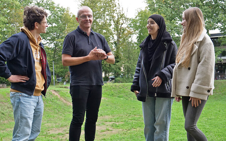 Prorektor Prof. Dr. Rainer Neumann auf dem Campus im Gespräch mit drei „Erstis“