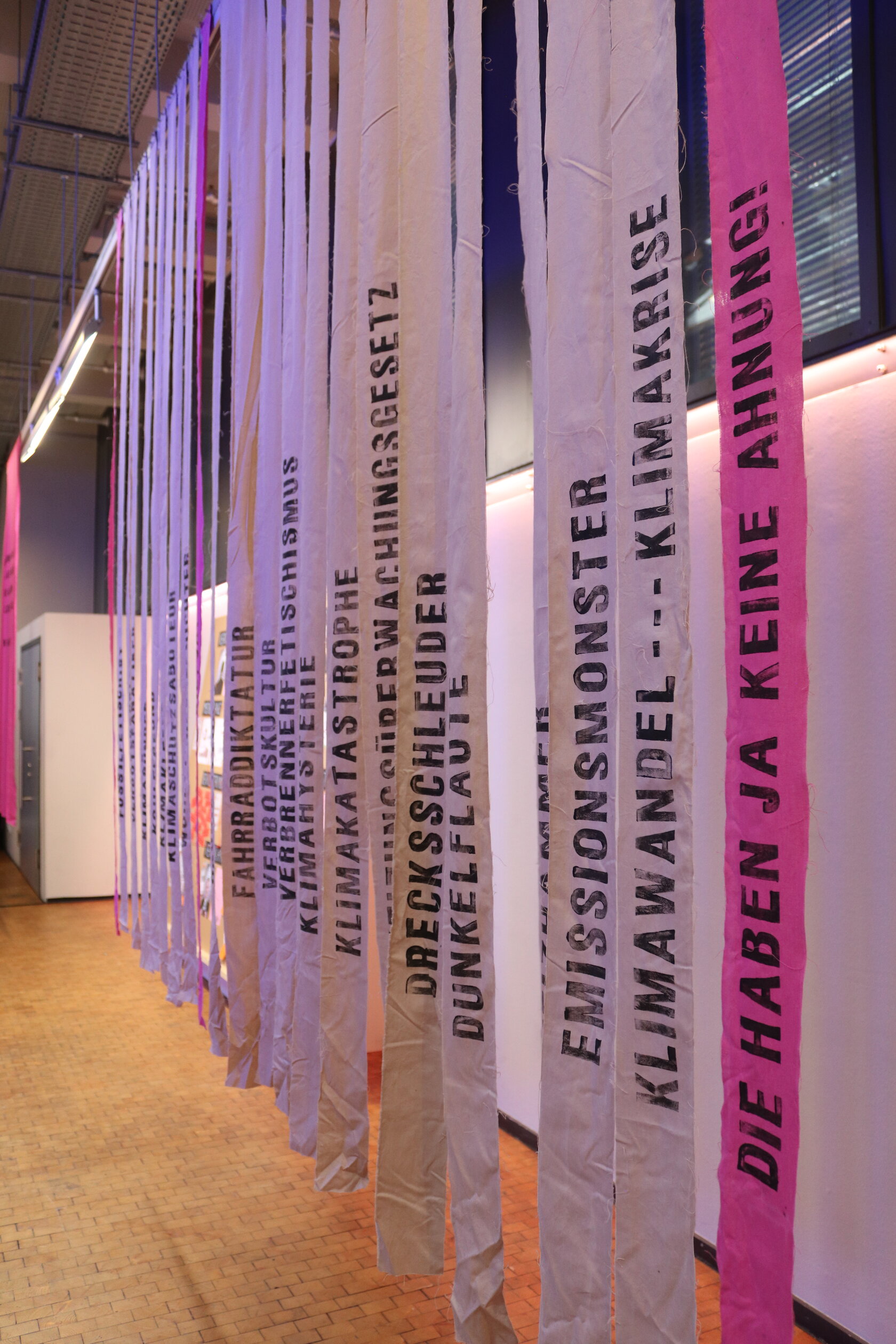 Stoffbahnen mit aufgestempelten Begriffen, wie "Emissionsmonster", "Klimawandel---Klimakrise" oder "Die haben ja keine Ahnung!", hängen von der Decke
