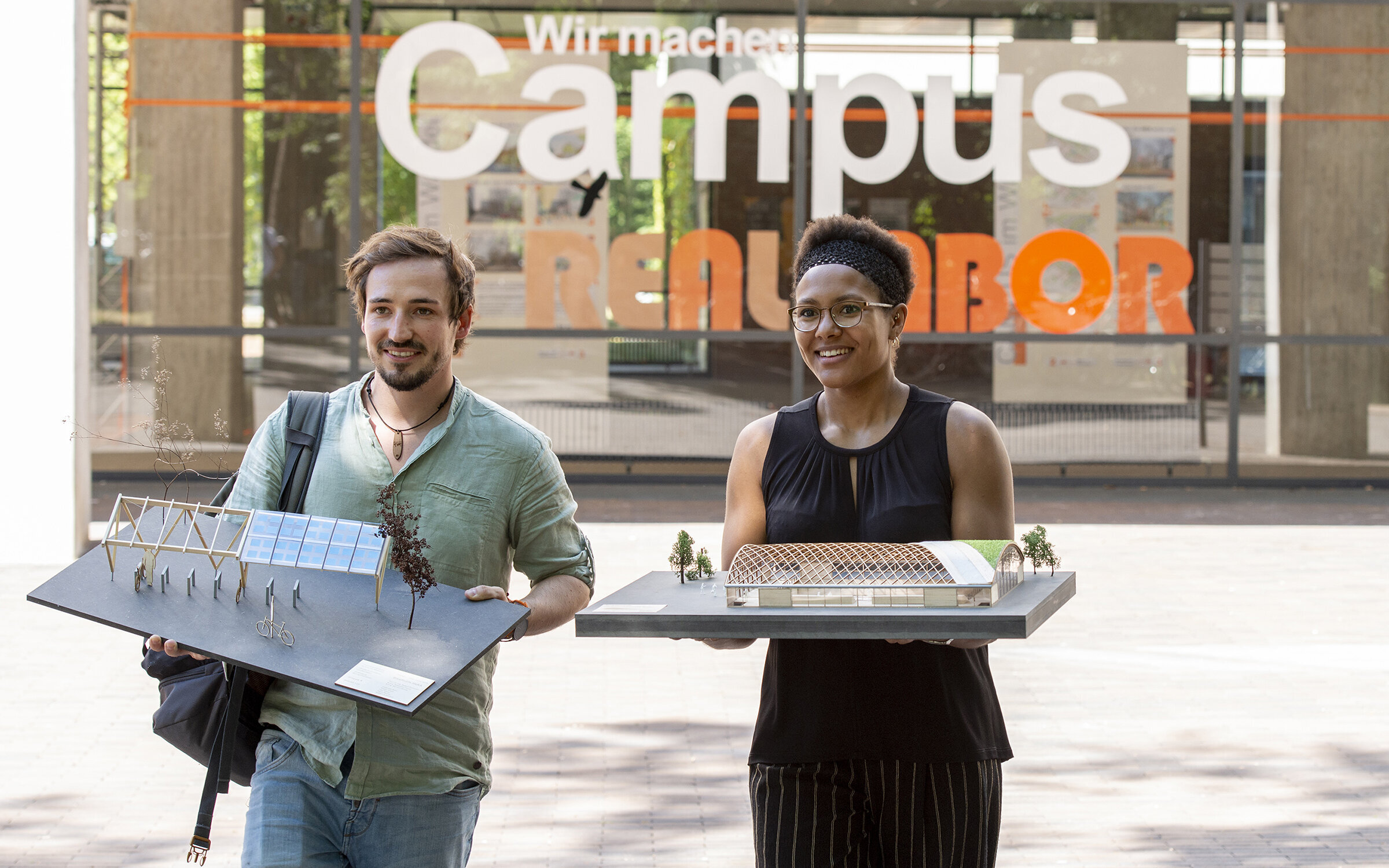 two students in front of the Civil Engineering building, carrying models of buildings two students in front of the Civil Engineering building, carrying models of buildings