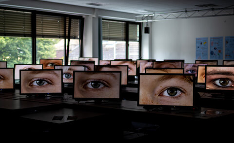 Raum voller Bildschirme, auf denen einzelne Augen zu sehen sind.