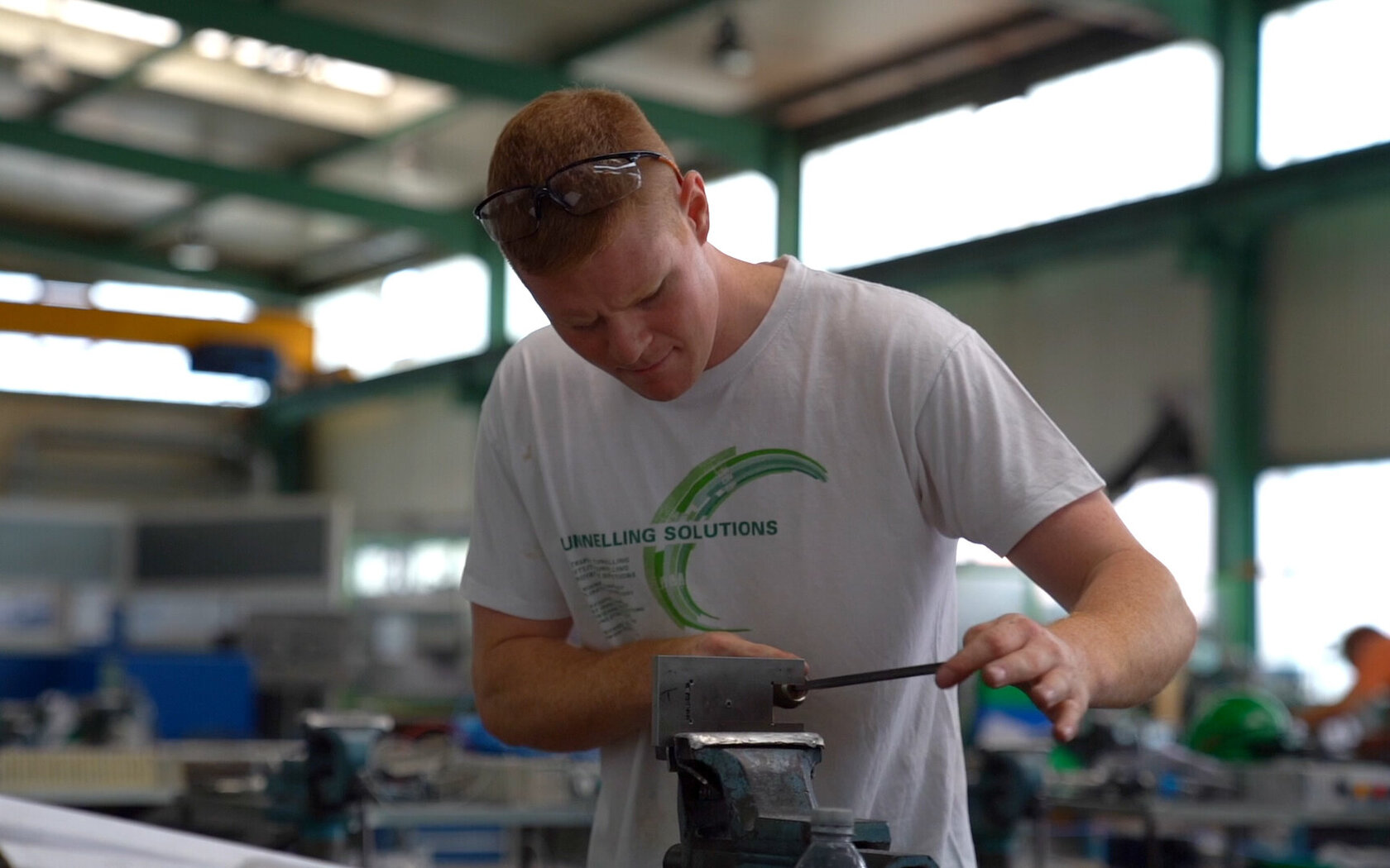 Student/Auszubildender arbeitet in der Werkhalle an einem Produktionsteil