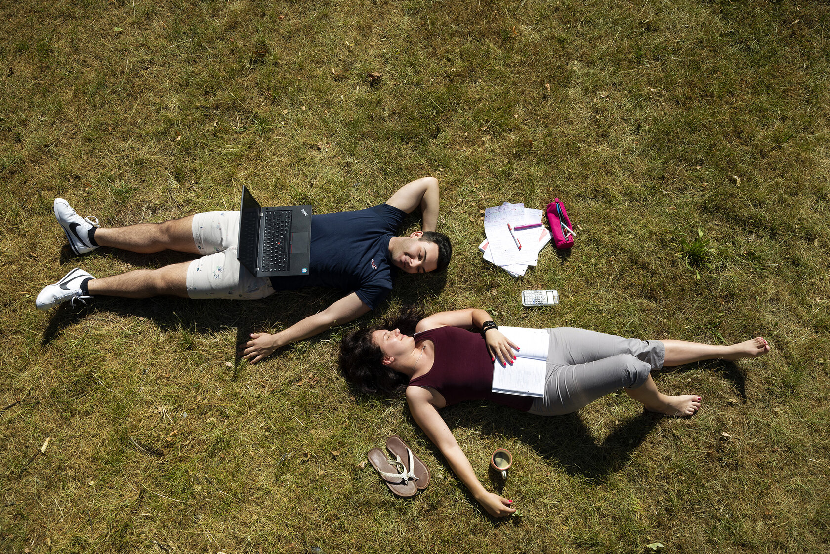 A couple relaxes on a meadow on campus